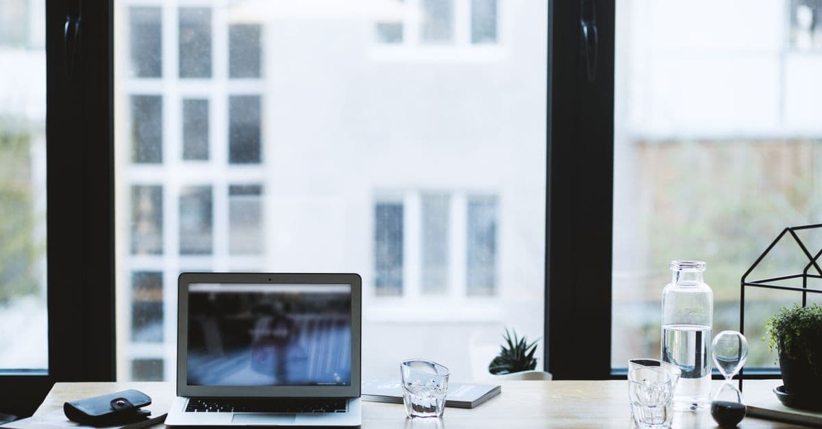 Laptop and notebook on a dedicated work desk beside a large window