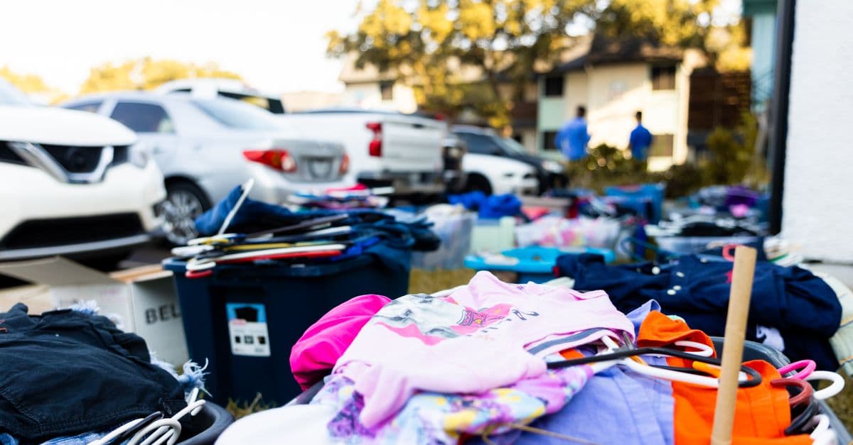 Used clothes and hangers displayed on tables at a neighborhood garage sale
